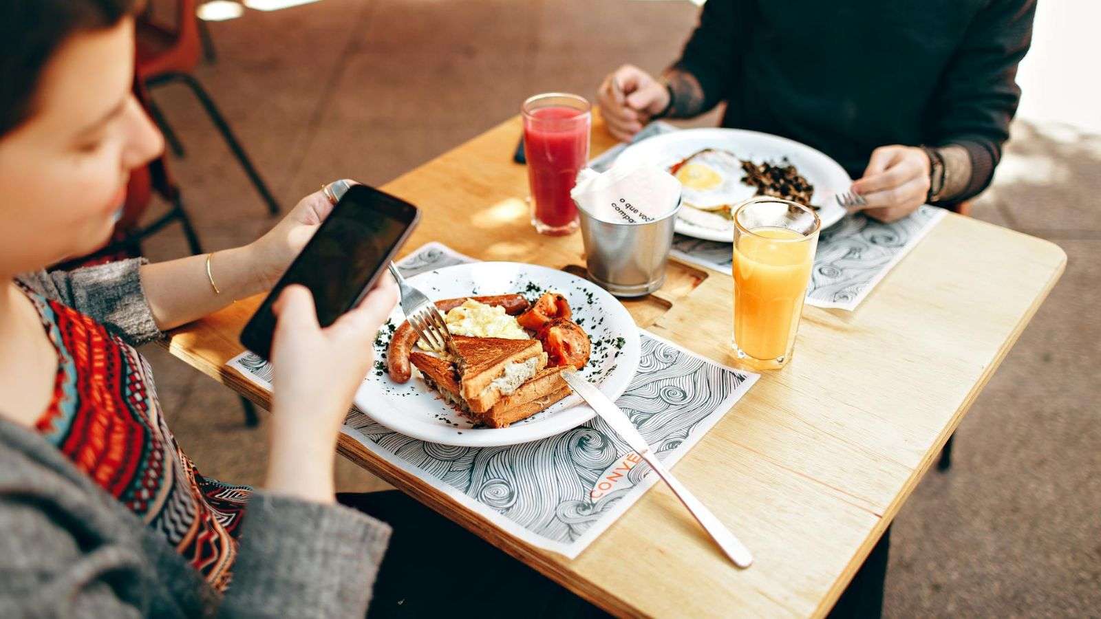 Persona fotografiando comida con su teléfono antes de comer.
