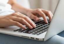 Manos escribiendo en una computadora portátil como parte del uso consciente de la inteligencia artificial