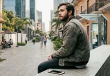 Joven en pausa reflexiva usando celular en un entorno cotidiano, representando la confianza digital