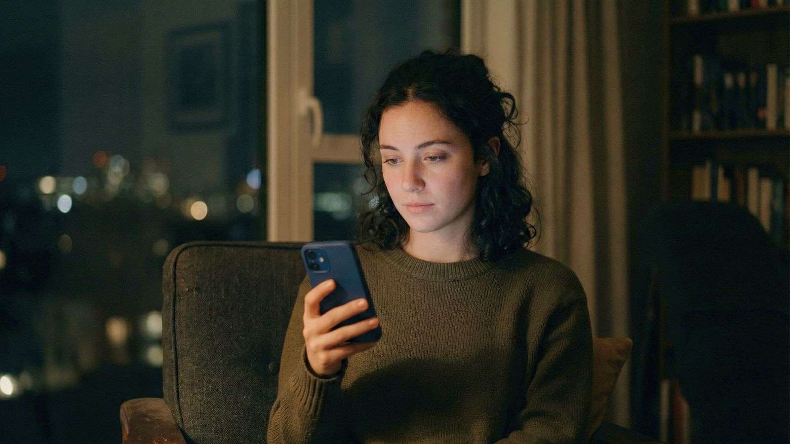 Persona mirando su celular iluminada por la luz de la pantalla