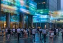 Cuando entendemos sin detenernos en lo digital Personas caminando en un entorno urbano con luces en movimiento, representando el flujo digital continuo