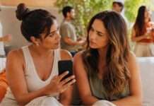 Dudar mejor: la nueva habilidad de la vida digital Dos mujeres jóvenes observan un celular con atención en una reunión informal al aire libre