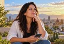 Mujer sola en una azotea contemporánea, con estilo ejecutivo casual, mientras consulta su teléfono en un momento de calma y reflexión.