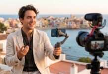 Influencers: cuando el alcance y la relevancia van por caminos distintos Creador de contenido de viajes se graba en un paisaje panorámico mientras una cámara en primer plano sugiere producción digital.